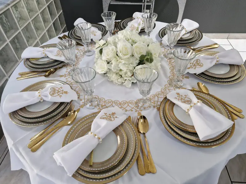 Exemple de table ronde dressée pour un événement, vaisselle dorée et bouquet de roses blanches